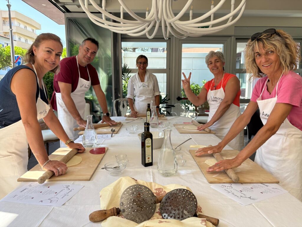 A group Italian cooking class rolling out pizza dough as an activity found at Lungomare Bike Hotel outside of cycling.