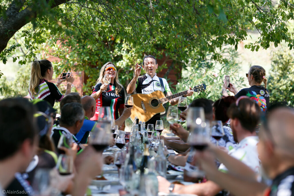 A group of cyclists enjoying a lunch together with wine and live music acting as a family where everyone is included.