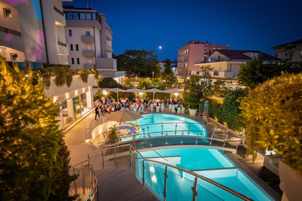 The outside pool and deck at Belvedere Bike Hotel in Riccione Italy showing family style dinner in a lovely setting