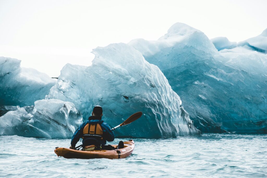 Kayaker floating through glacier ice 